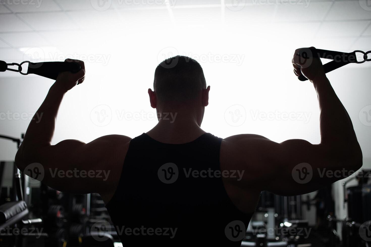 Portrait of an athlete, a sports man coach does an exercise on simulator in the gym. Healthy active lifestyle, shakes muscles. silhouette photo