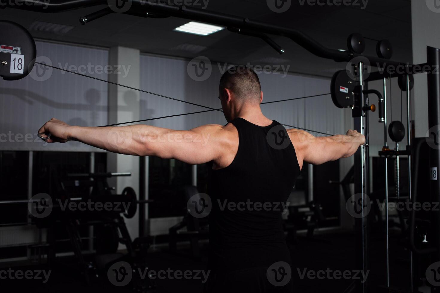 Portrait of an athlete, a sports man coach does an exercise on simulator in the gym. Healthy active lifestyle, shakes muscles. rear view photo