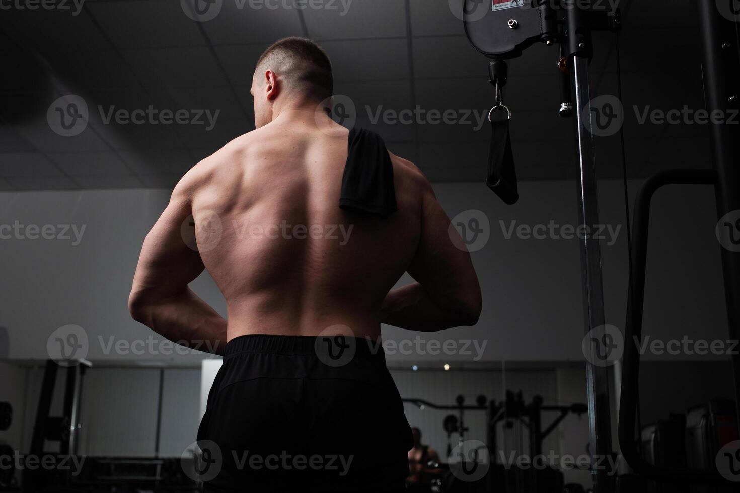 Portrait of a beautiful male athlete bodybuilder in gym, low key, darkness. Posing, coach. power, strength, abstraction background photo