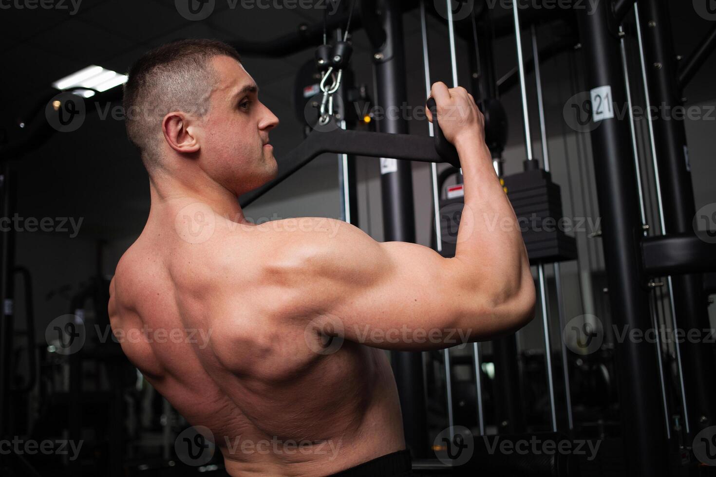 portrait of a handsome male coach in gym. The athlete does an exercise on the simulator in the gym. Builds muscle, plays sports, a healthy lifestyle. torso photo