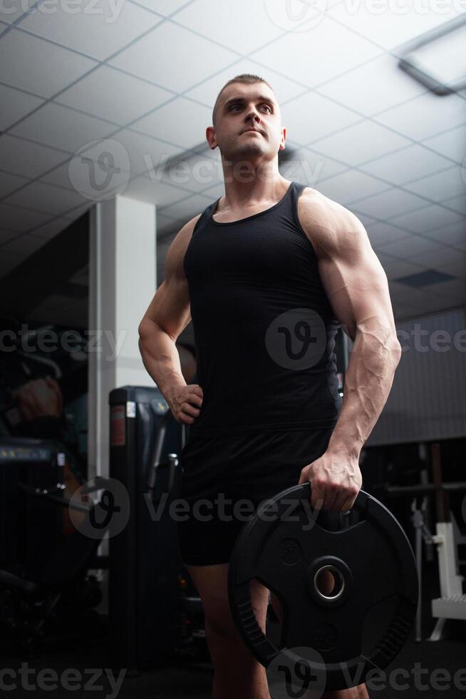 retrato de un hermoso hombre en gimnasia. entrenador, atleta, carrocero, muscular sexy cuerpo, oscuridad. grave foto