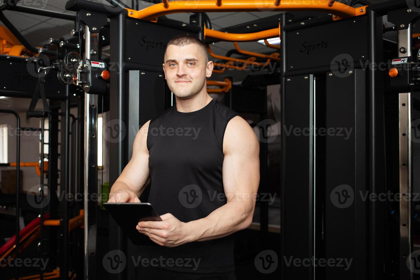 young handsome coach with a tablet in his hands. Coaching, individual courses of sports and weight loss. Modern technology, records the results, social network, Internet. Smiling photo