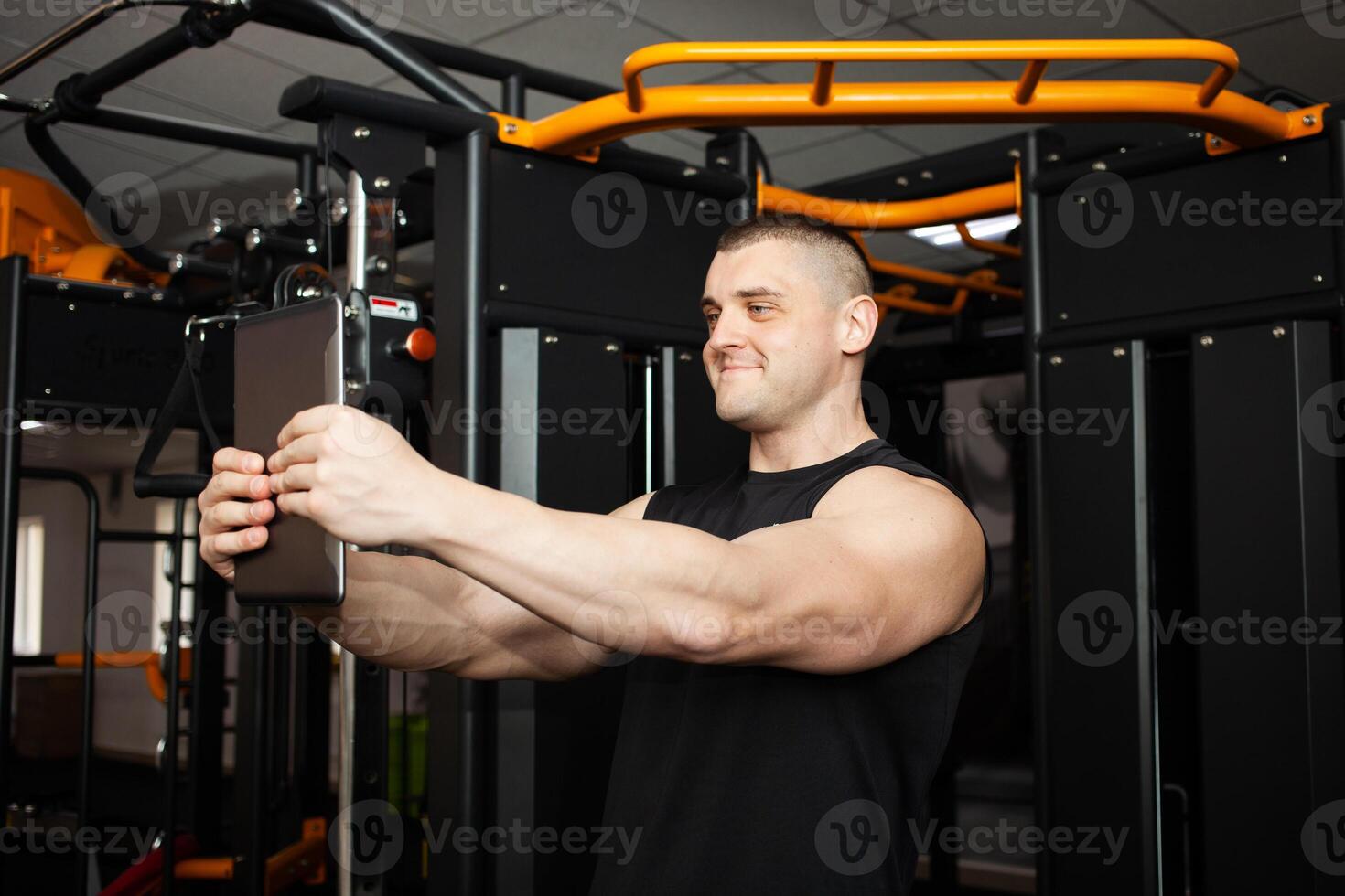 young handsome coach is photographed on a tablet, communicates with friends, rests after a workout in gym, social networks, Internet, advertising. Video call, videos, indoor concept. photo
