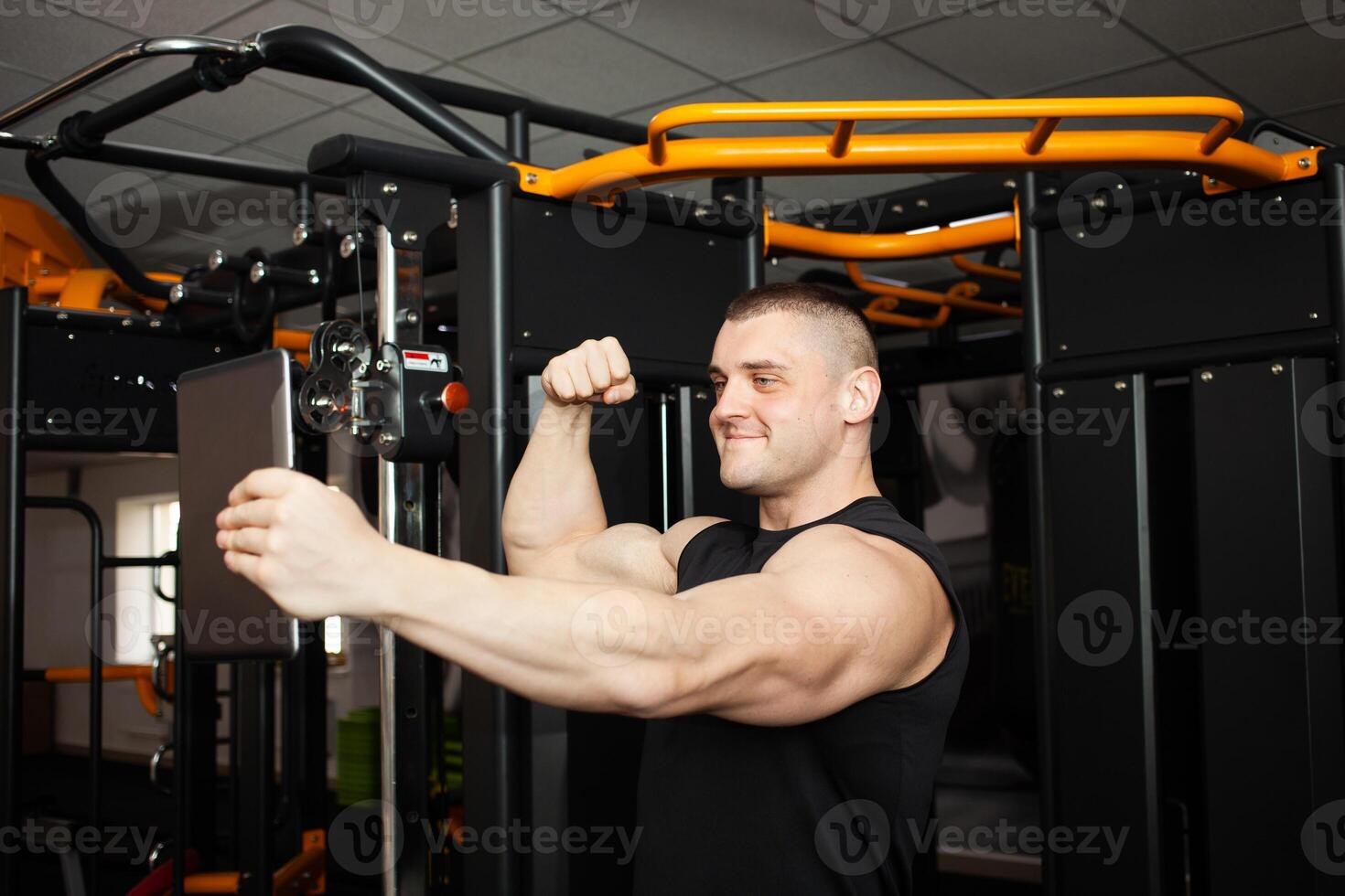 joven hermoso entrenador es fotografiado en un tableta, comunica con amigos, descansa después un rutina de ejercicio en gimnasia, social redes, Internet, publicidad. vídeo llamar, vídeos, interior concepto. sonriente foto