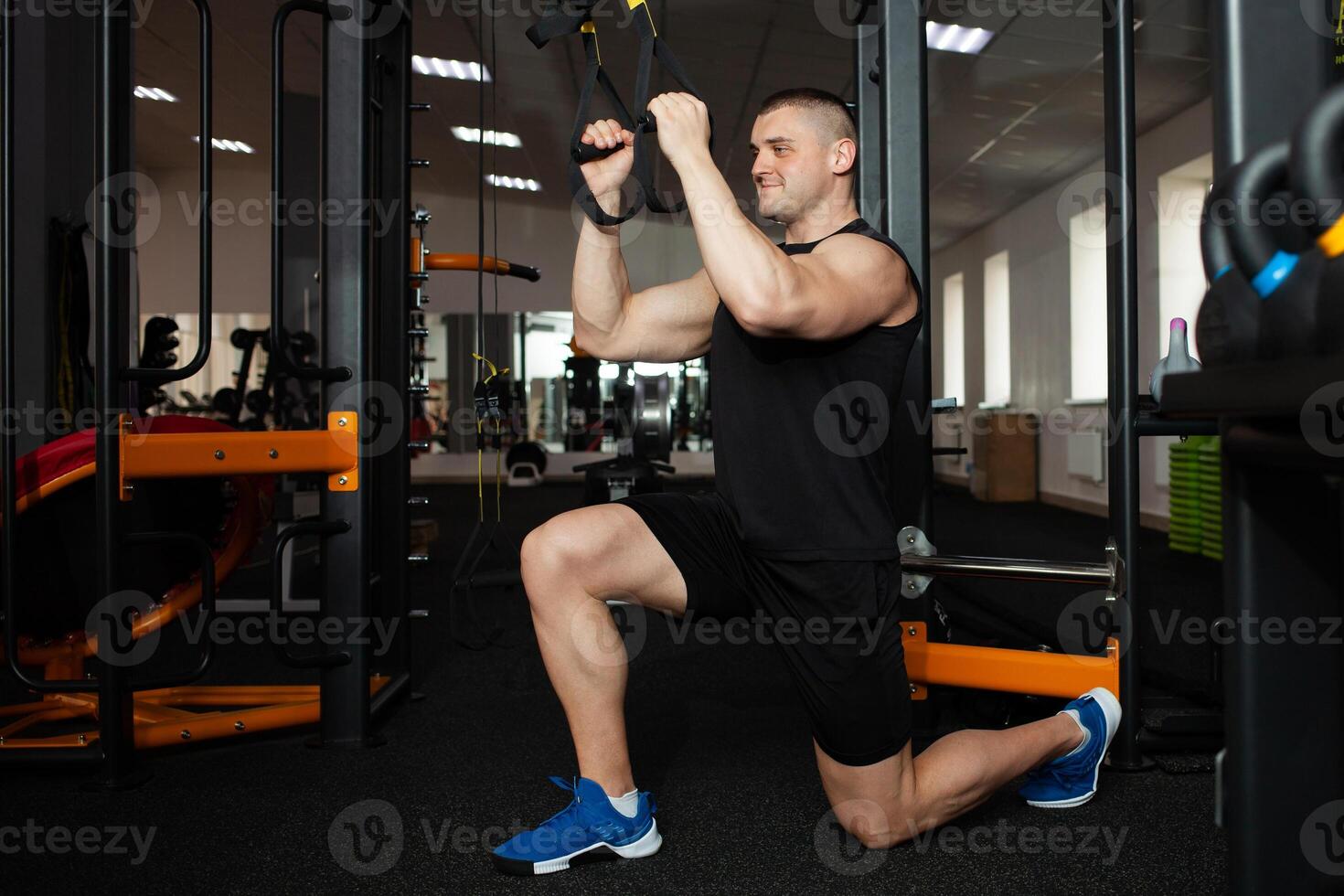 A beautiful trainer performs exercises on simulator, squats, push-ups on weight, muscular body. Athlete in the gym, coaching, individual weight loss courses, sports, advertising. Smiling photo