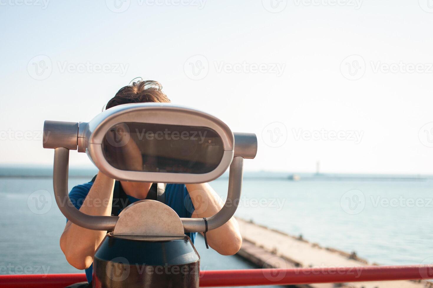 man looks through stationary binoculars. Binoscope on observation deck near sea. seaport in Odessa. Expensive yachts on the pier. Commercial machine, vending business. tourist travels photo