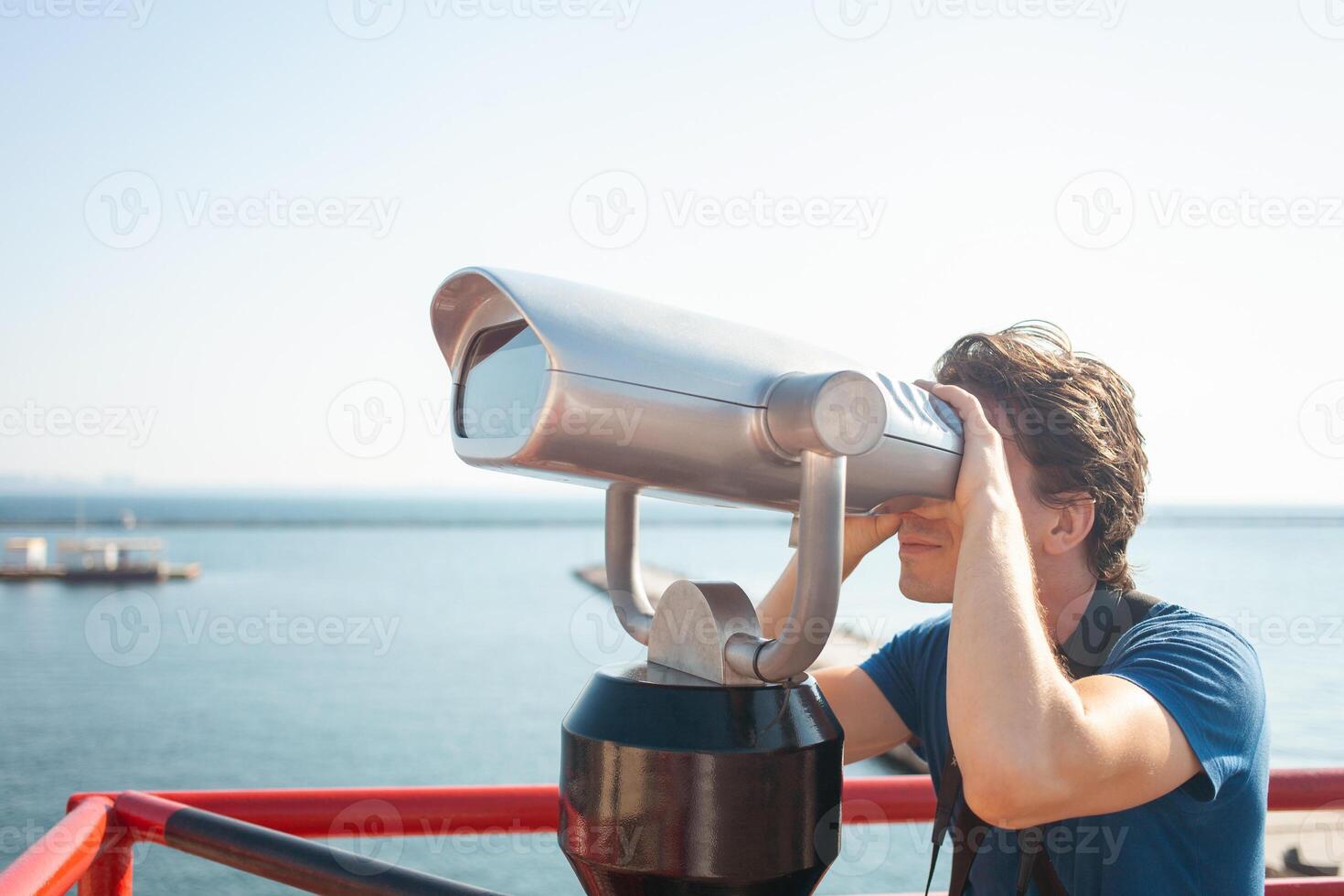 man looks through stationary binoculars. Binoscope on observation deck near sea. seaport in Odessa. Expensive yachts on the pier. Commercial machine, vending business. sky photo