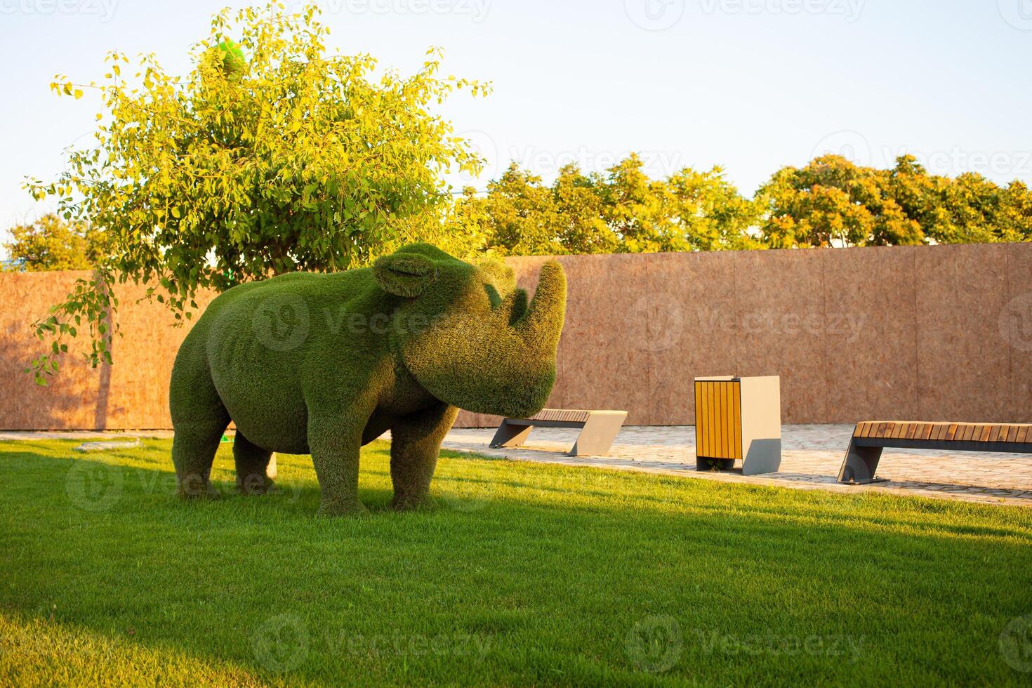 Beautiful rhinoceros made of grass, landscape design, animal figures from bushes. Mowed lawn photo