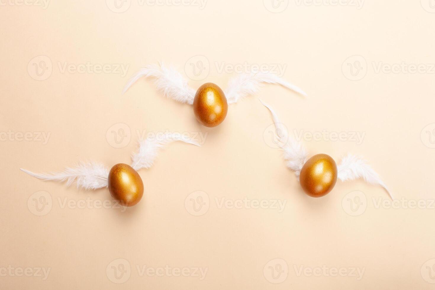 Empty space for text, a banner of happy Easter. Painted golden eggs, white feathers. copy space flat lay top view eggs with wings fly away from the nest photo