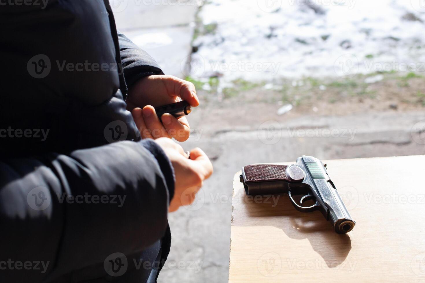 A man charges a gun with bullets. Danger, murder, firearms, shooting range, sports entertainment. photo