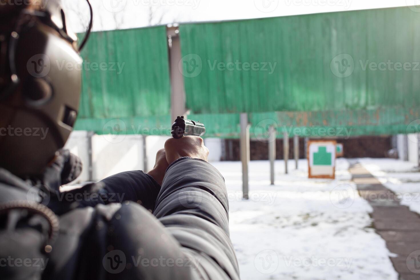 A man is aiming at the target. Tyre outside the door. Winter. Sports entertainment, firearms. photo