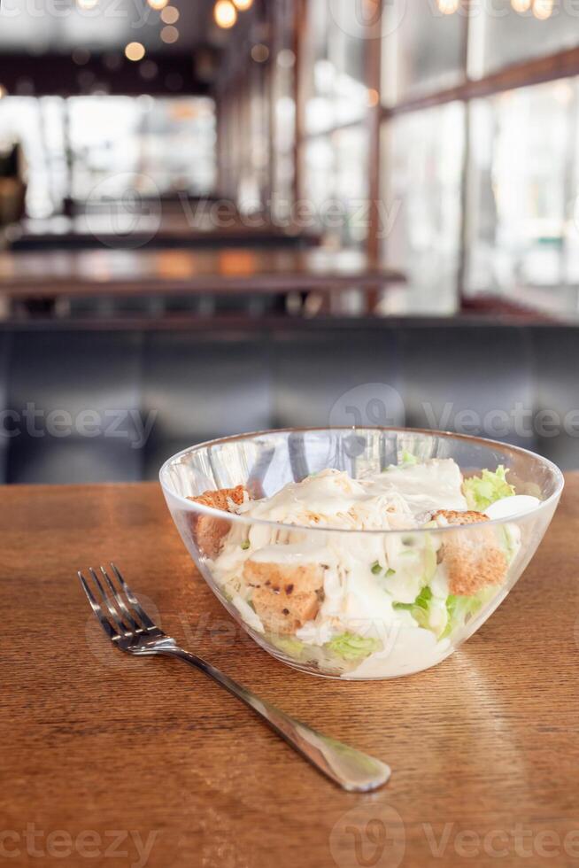 Caesar salad in a glass plate. Salad with fried chicken, salad, toast, sauce, tomatoes, cheese. Delicious breakfast, dinner, lunch in a cafe. Snack in the restaurant. photo