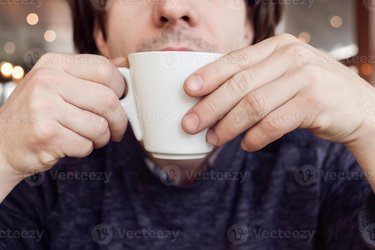 A man drinks coffee in a cafe, a restaurant. interior, natural sunlight, blurred background, sideways. Snack, breakfast. Lunch break. photo