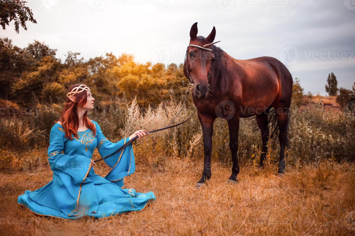 Beautiful young female elf with long dark wavy hair petting her horse resting in the woods forest nymph stroking her horse care pet love animals harmony caring owner gentle creature myth photo
