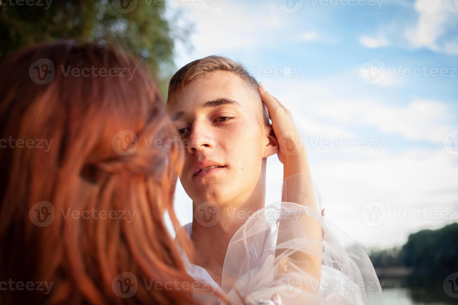 Portrait of the groom against the river and forest. A man looks at his fiancee. photo