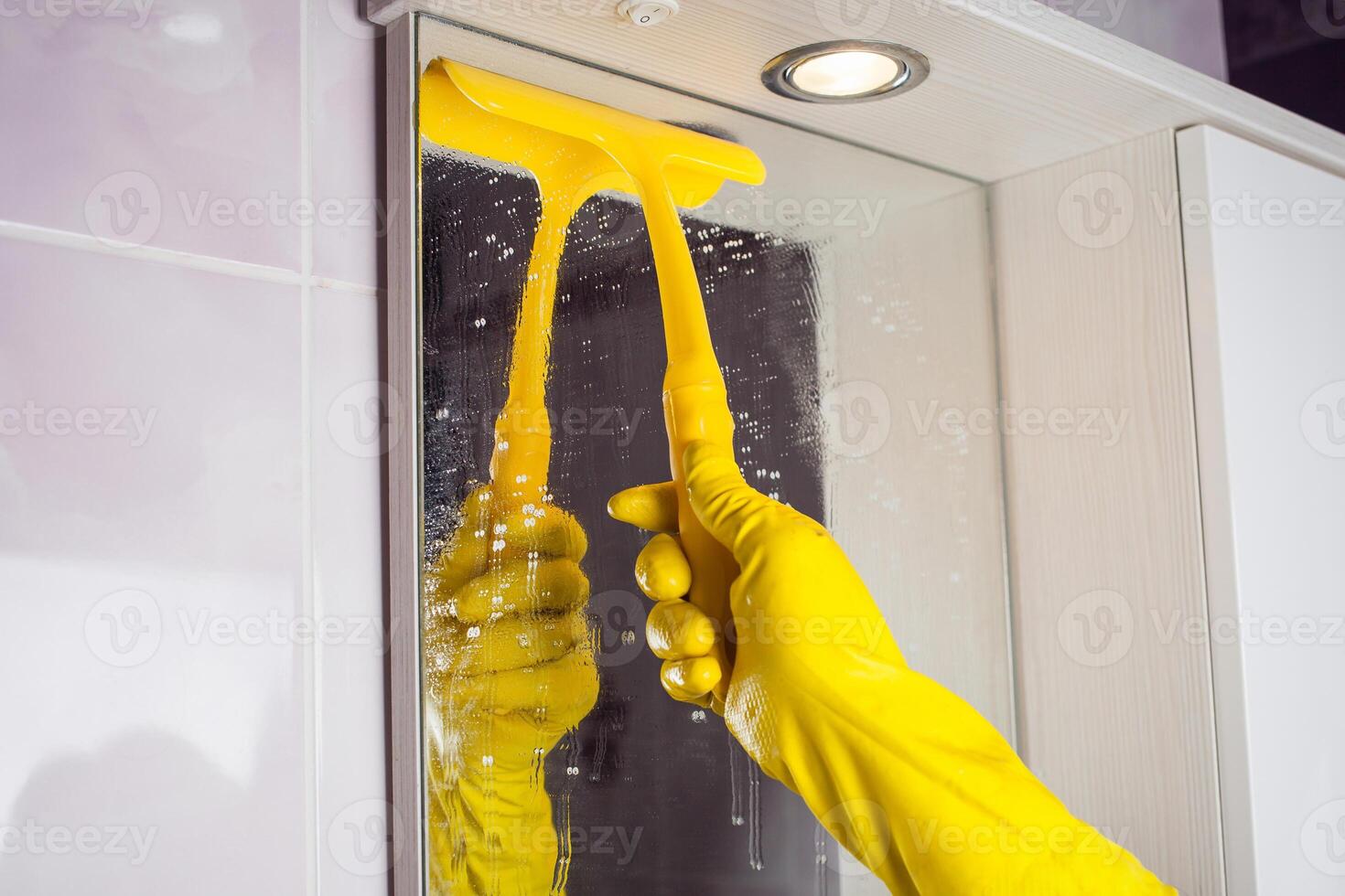 Maid with rubber glove cleaning tap and sink. photo