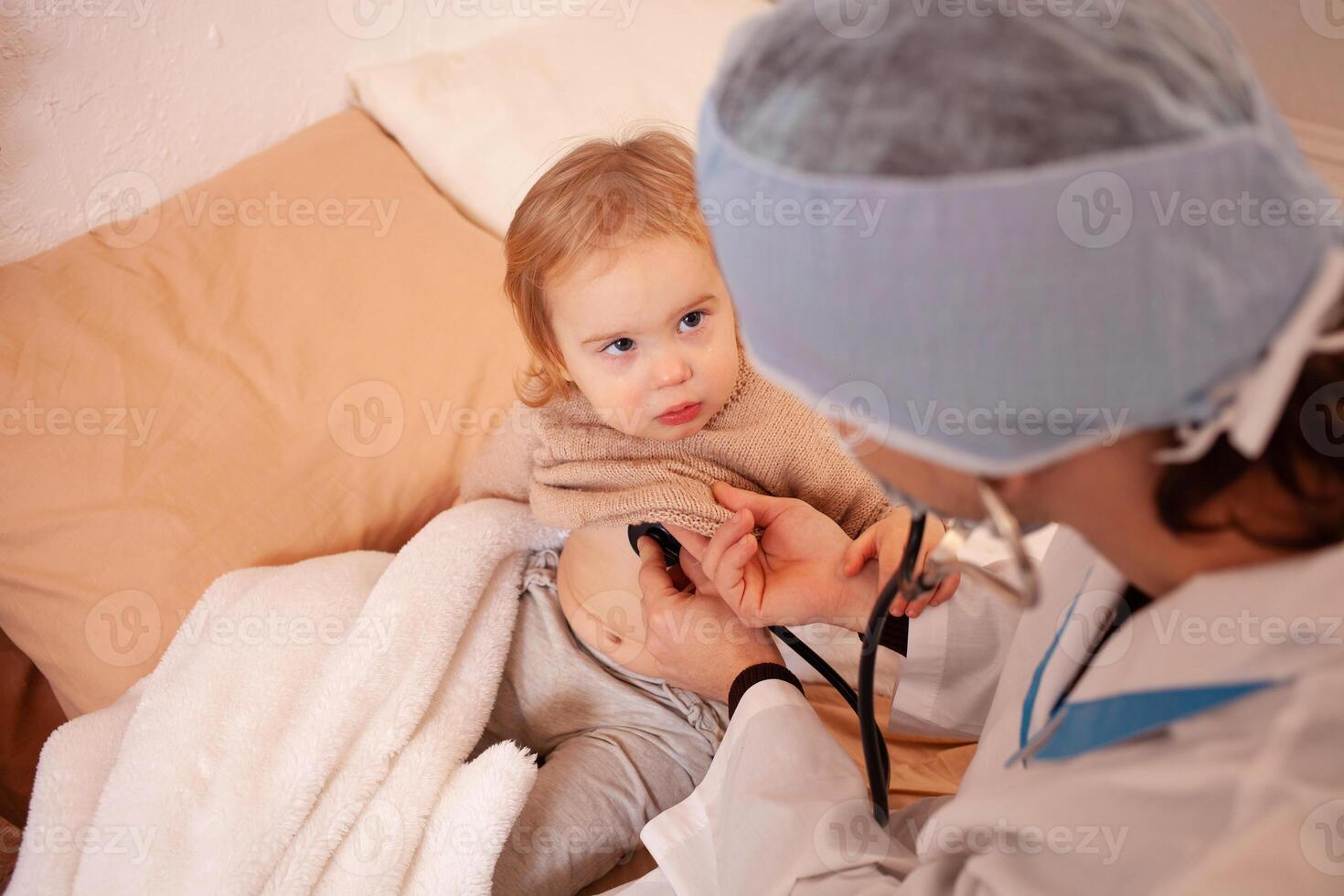 The doctor listens to the heart and lungs of a little girl. Sick baby, home quarantine, coronavirus, covid. photo