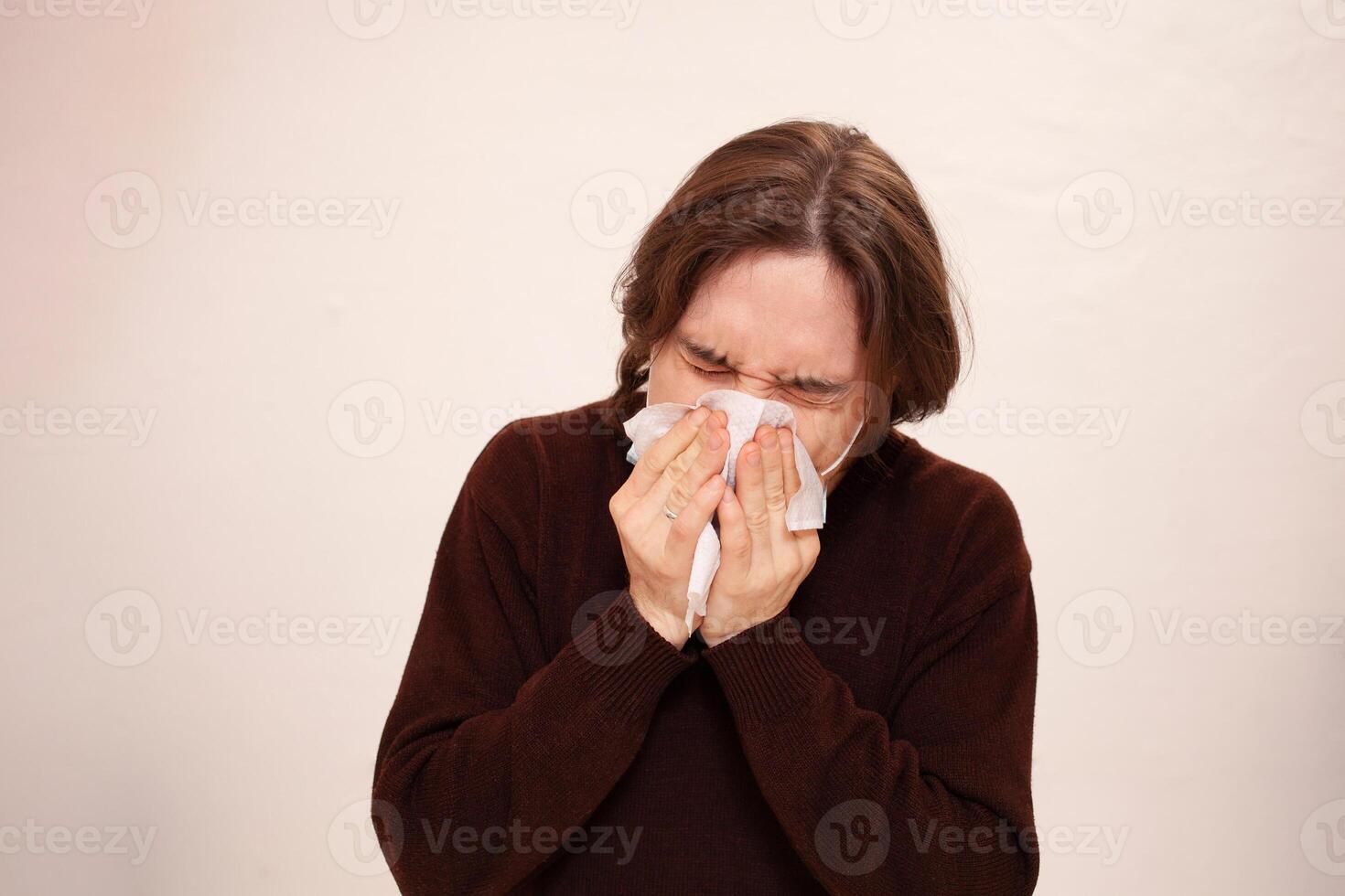 A man sneezes, a medical mask. Empty space for text on a white background. A sick man in home quarantine. Coronavirus photo