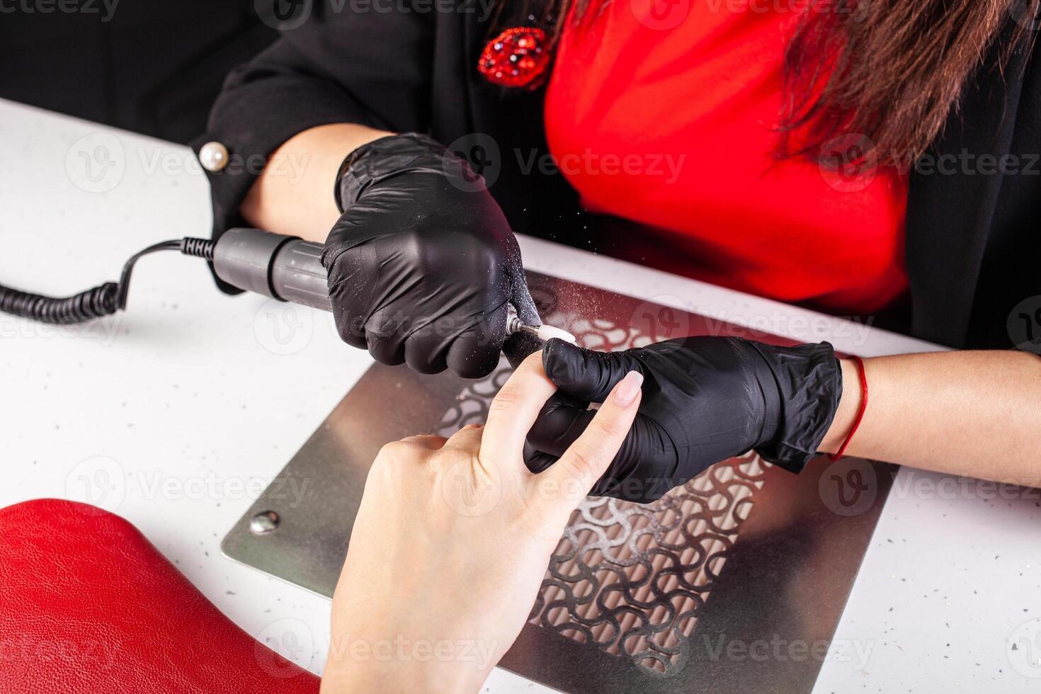 The manicurist holds hands of the client in beauty salon on desktop for manicure with nail polishes, napkins, creams and lighting instruments photo