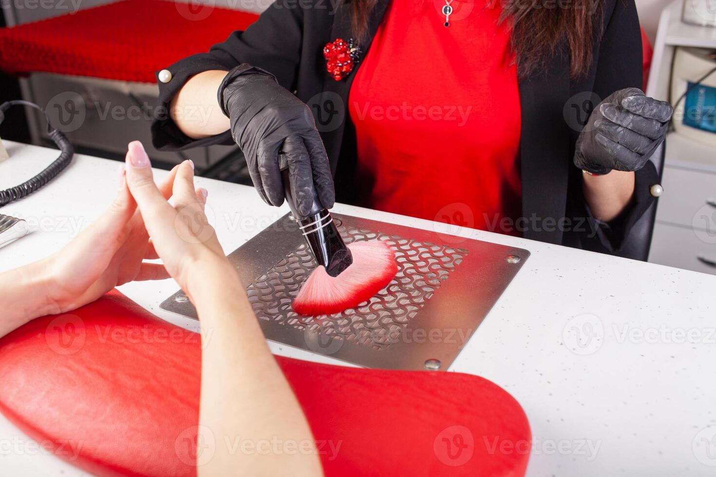 The manicurist holds hands of the client in beauty salon on desktop for manicure with nail polishes, napkins, creams and lighting instruments photo