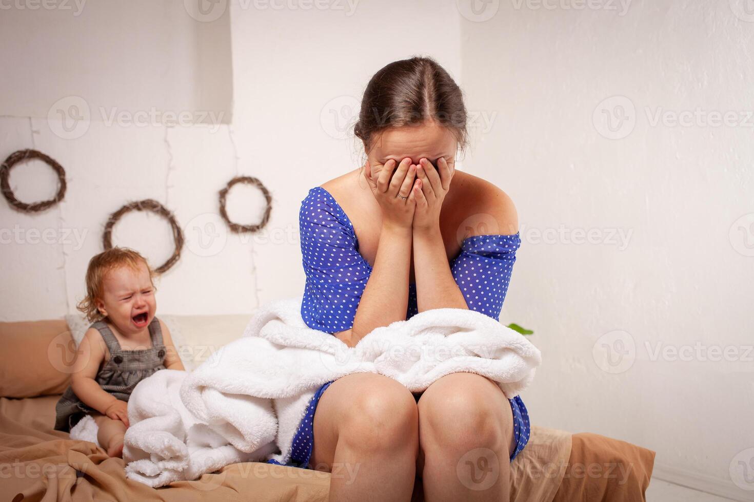 Mom is tired of the baby, wants to rest and sleep. The child screams, hysterical. The woman is tired of the child's cry, she does not want to hear. A one-year-old girl yells from a toothache. photo