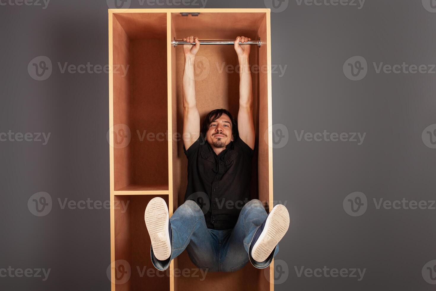 A man hangs in a cupboard on a pipe, funny, a test of the closet for strength. photo