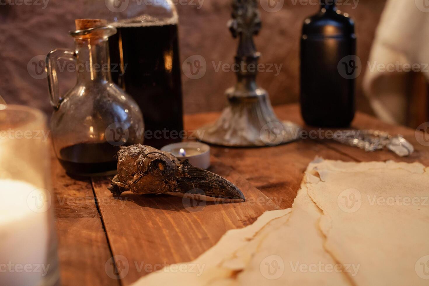 Photo zone in the studio for Halloween. Dramatic scenery for All Saints Day celebrations. The skull is decorated with beads and stones, candles, ink, crow's skull, old parchment on atable.