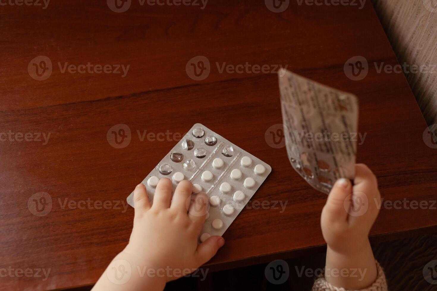 The child took out pills, the girl is playing with medical medicine, a one-year-old child can eat pills and not wake up, poison. Danger in the house, medicines are dangerous for young children. photo