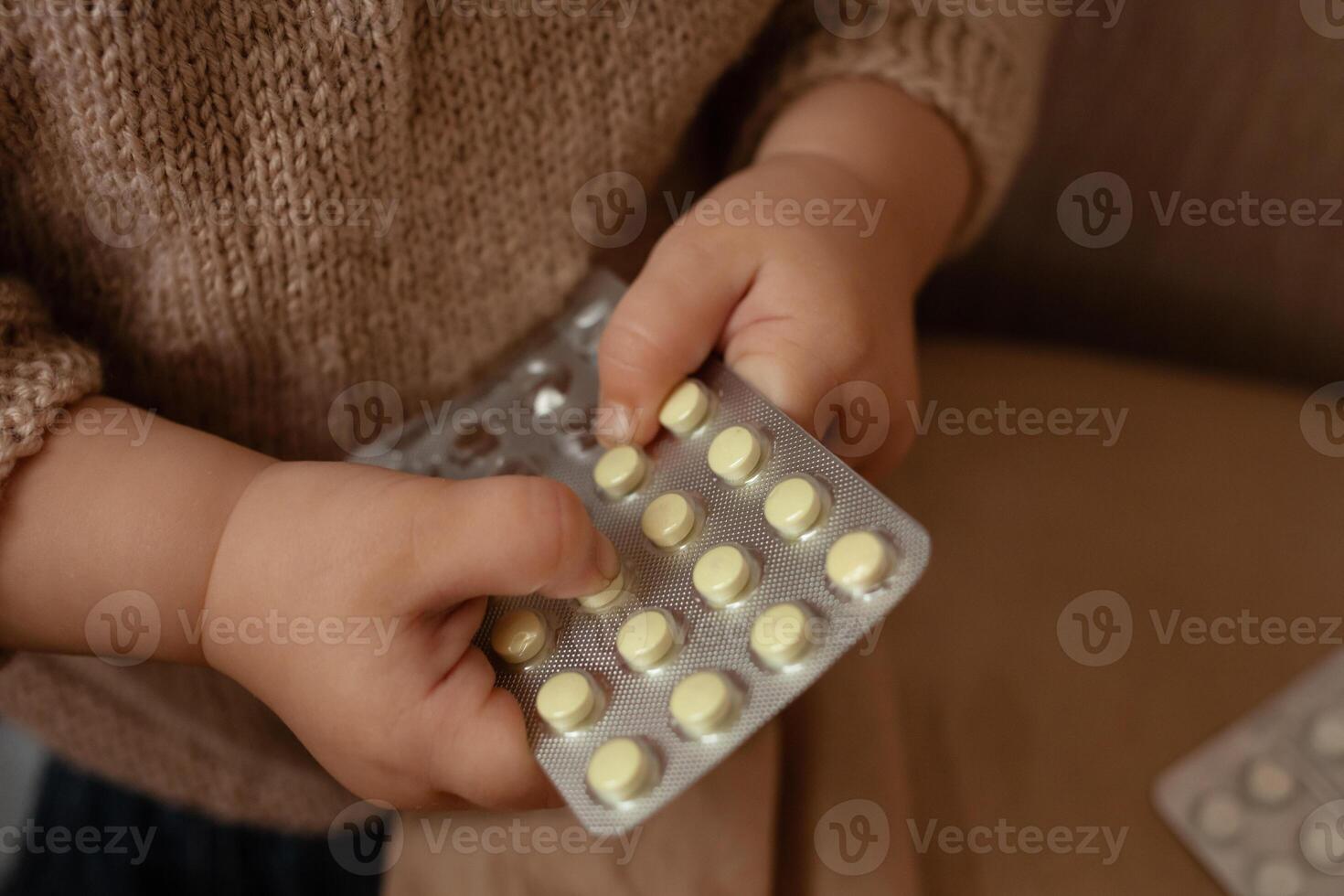 The child took out pills, the girl is playing with medical medicine, a one-year-old child can eat pills and not wake up, poison. Danger in the house, medicines are dangerous for young children. photo