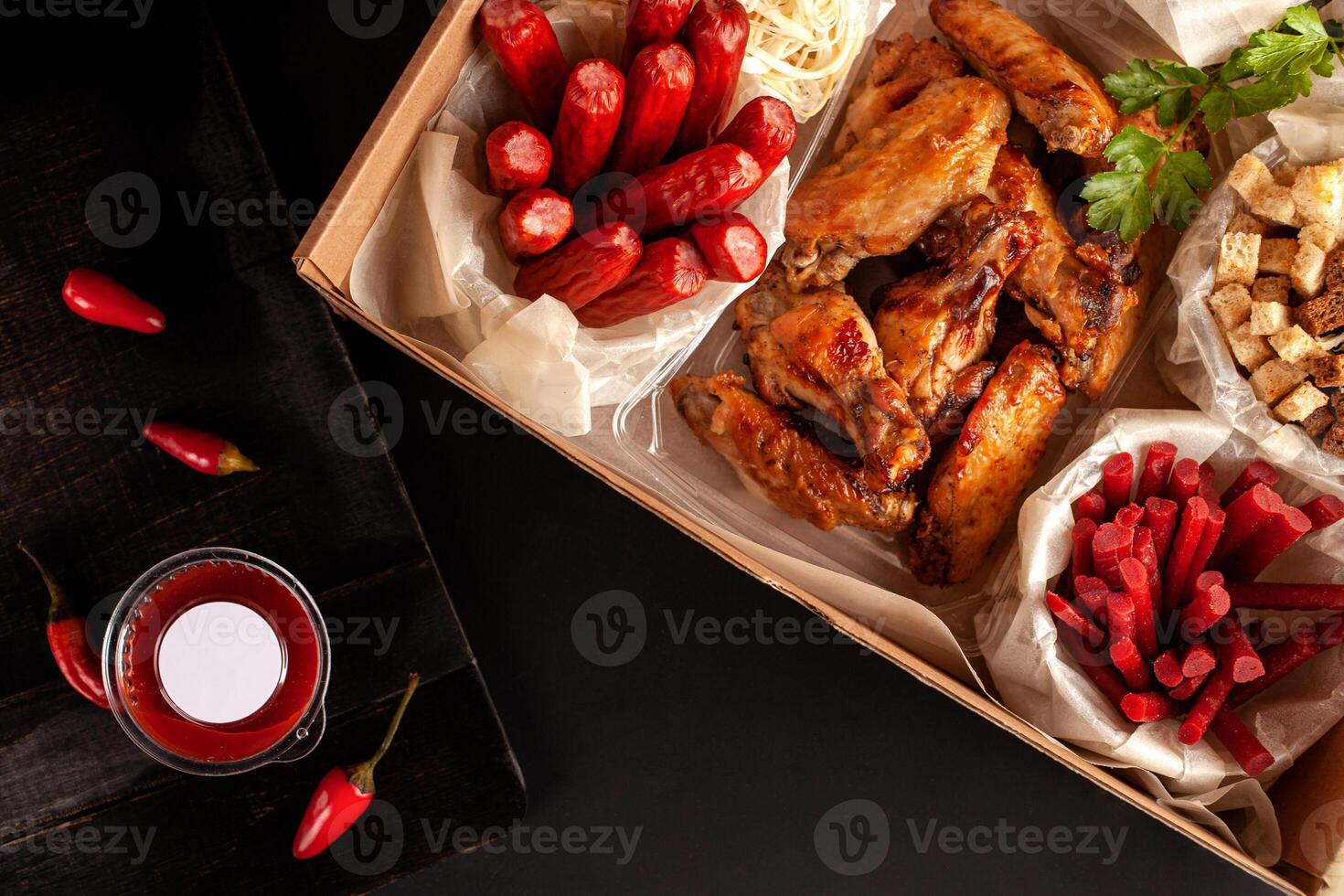 Red peppers on a black background in a low key. Food delivery from markets and restaurants. Meal for a week on quarantine. Chicken wings, shrimp crackers sausages to beer at the craft box photo