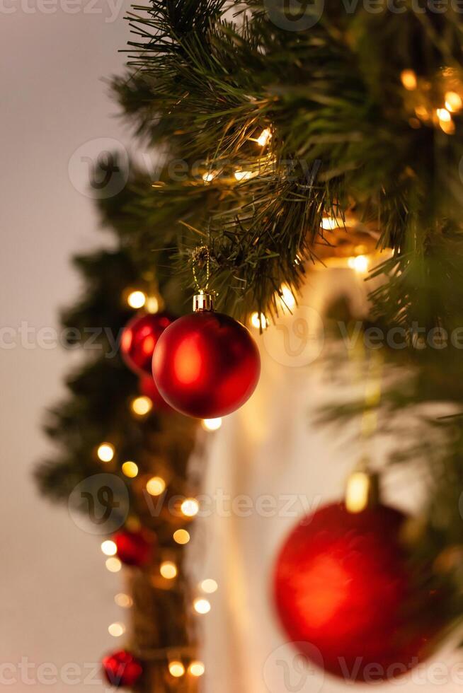 Christmas photo zone, yellow lights, sideways. Red Christmas balls on the tree branch. New Year's wreath.