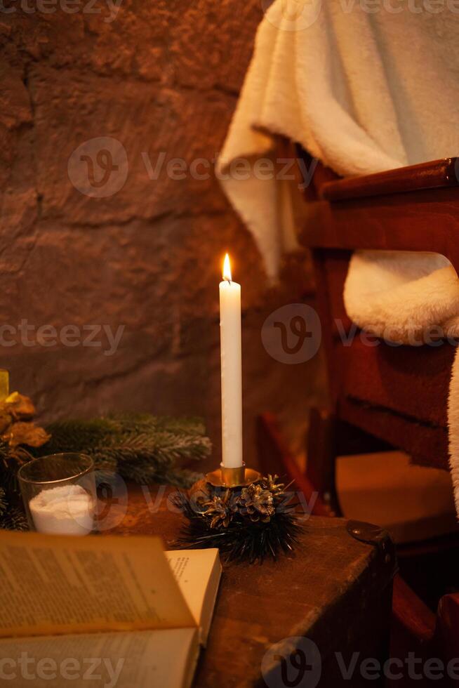 New Year's photo zone in the studio. A chair, a Christmas tree with balls and cones. Yellow garland, lights, candles, lamps, books. Home interior for Christmas.