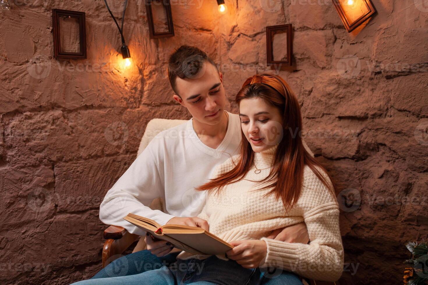 A couple in love, a guy and a girl reading a book. Christmas decorations in the photo studio Young teens