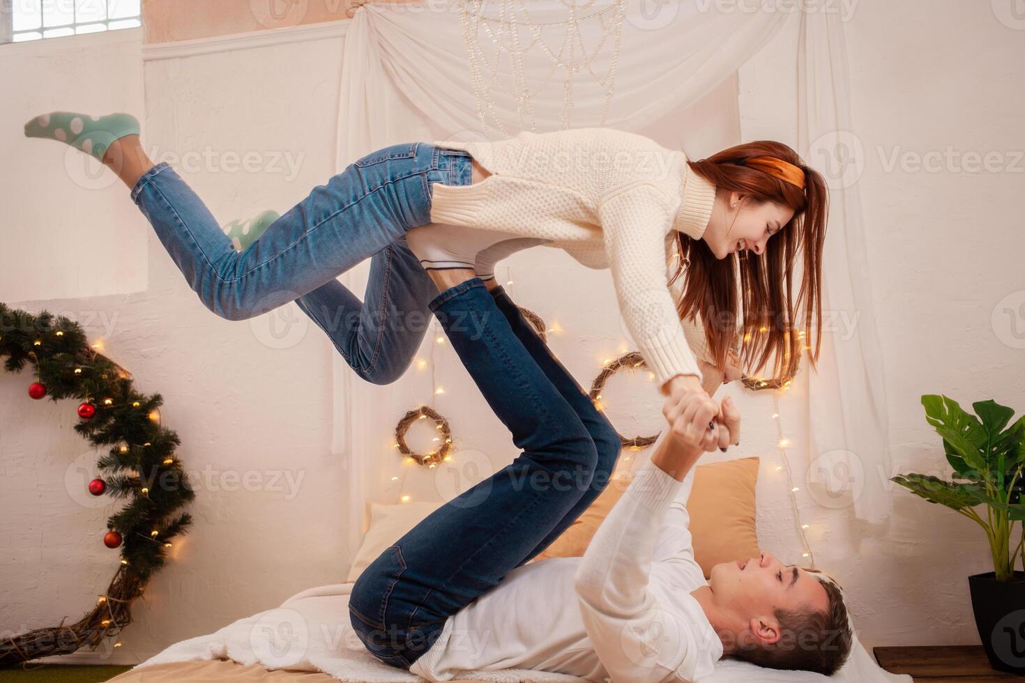 A young couple in love in a photo studio. Christmas scenery, guy and girl love each other. Posing for models in the studio on New Year's Eve. People portray a plane, a funny girl, a fun posing