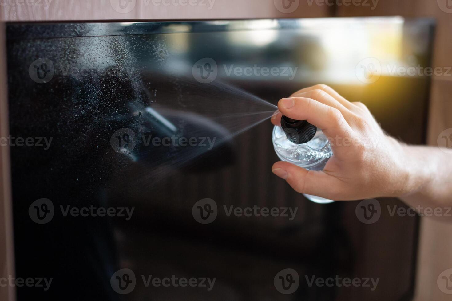 The man cleans the TV from the dust with a alcohol solution photo