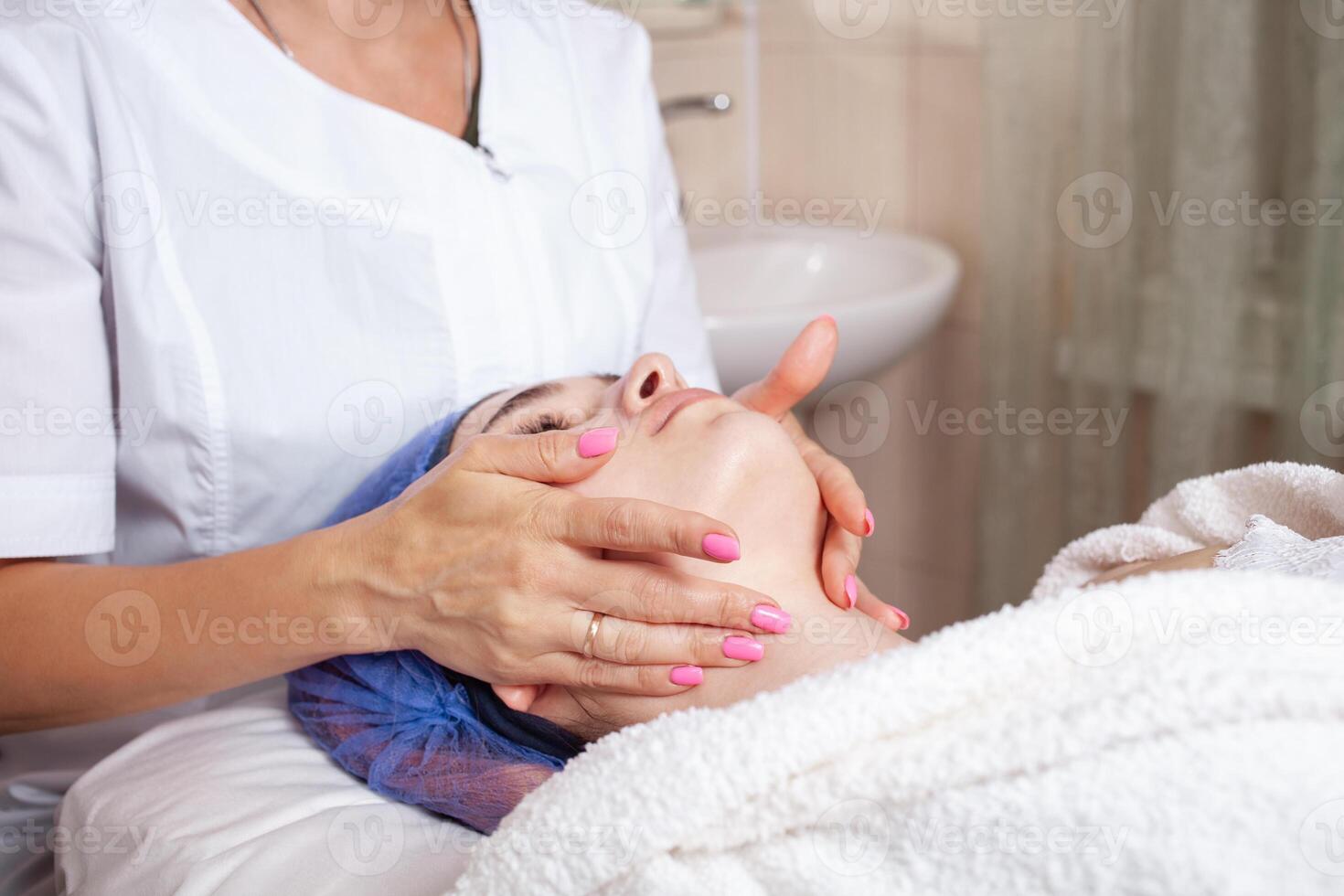 The beautician massages the face in the beauty salon photo