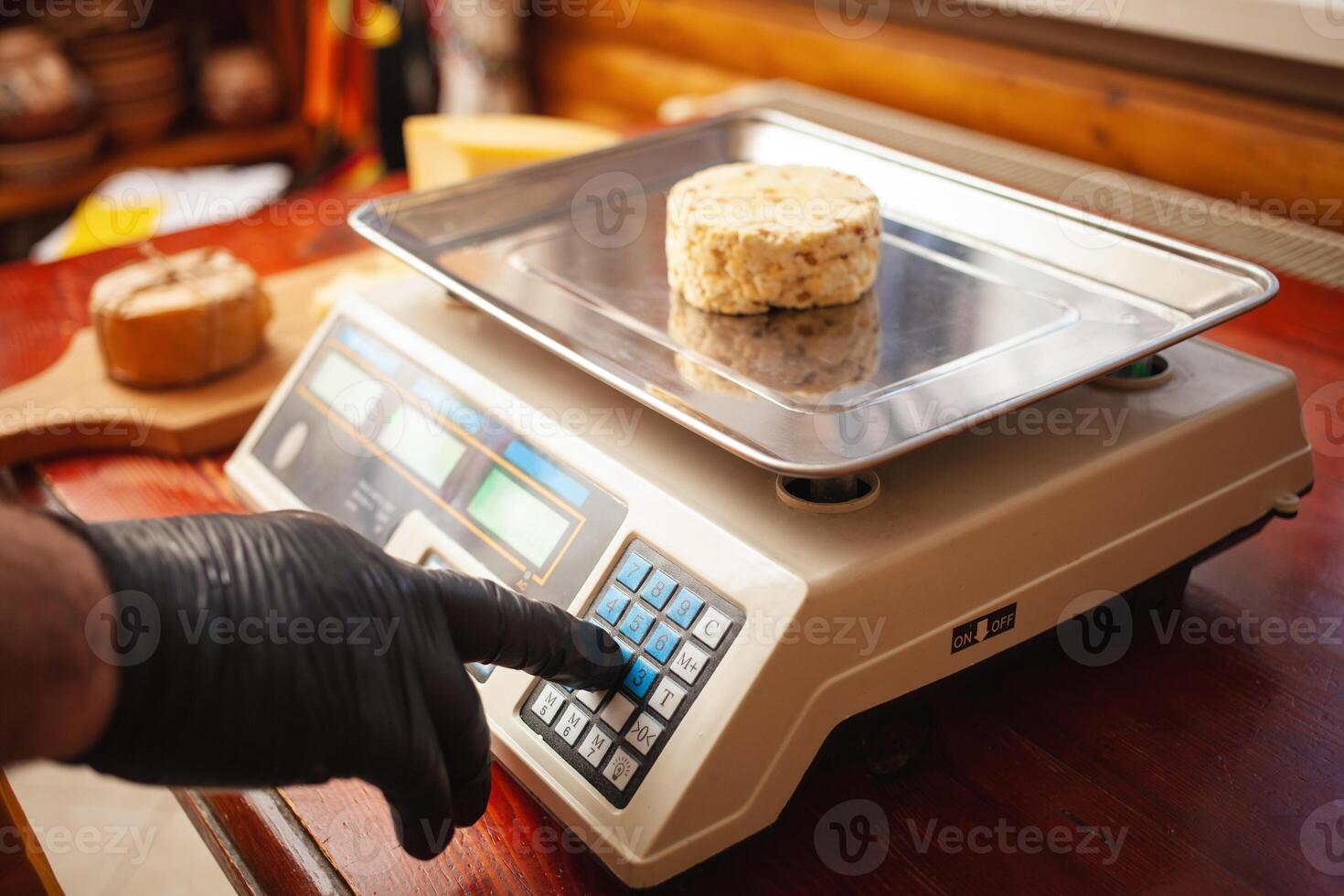 cheesemaker weighs cheese on scales, home production, business. photo