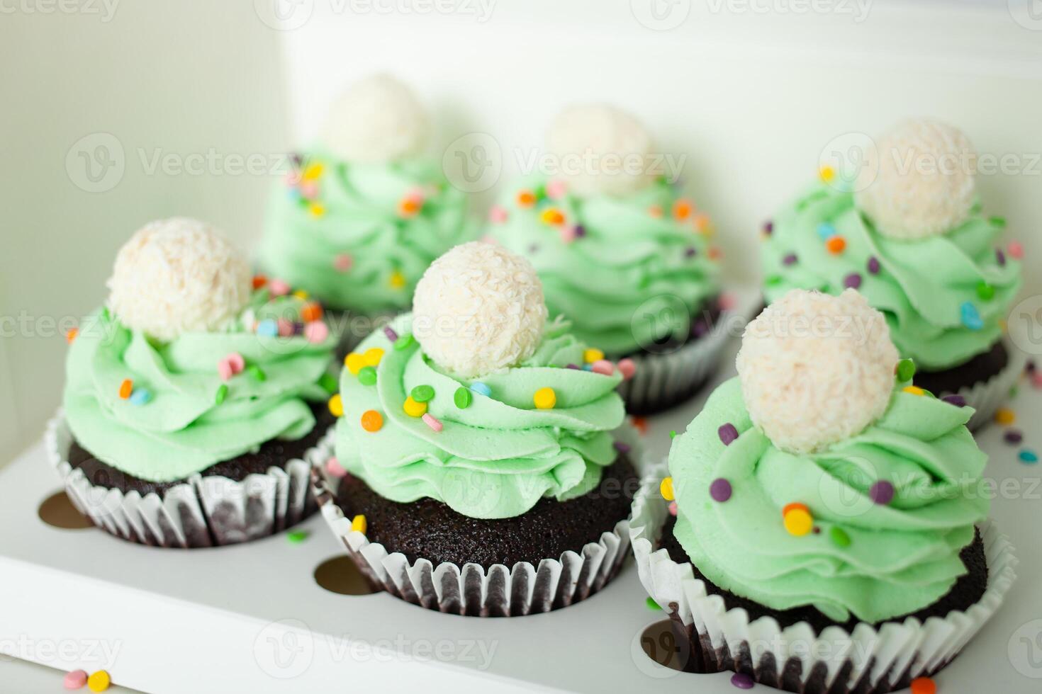 pastry chef professional prepared cupcakes in form of Christmas trees. Delicious sweets for any holiday, gift. Green whipped cream. photo