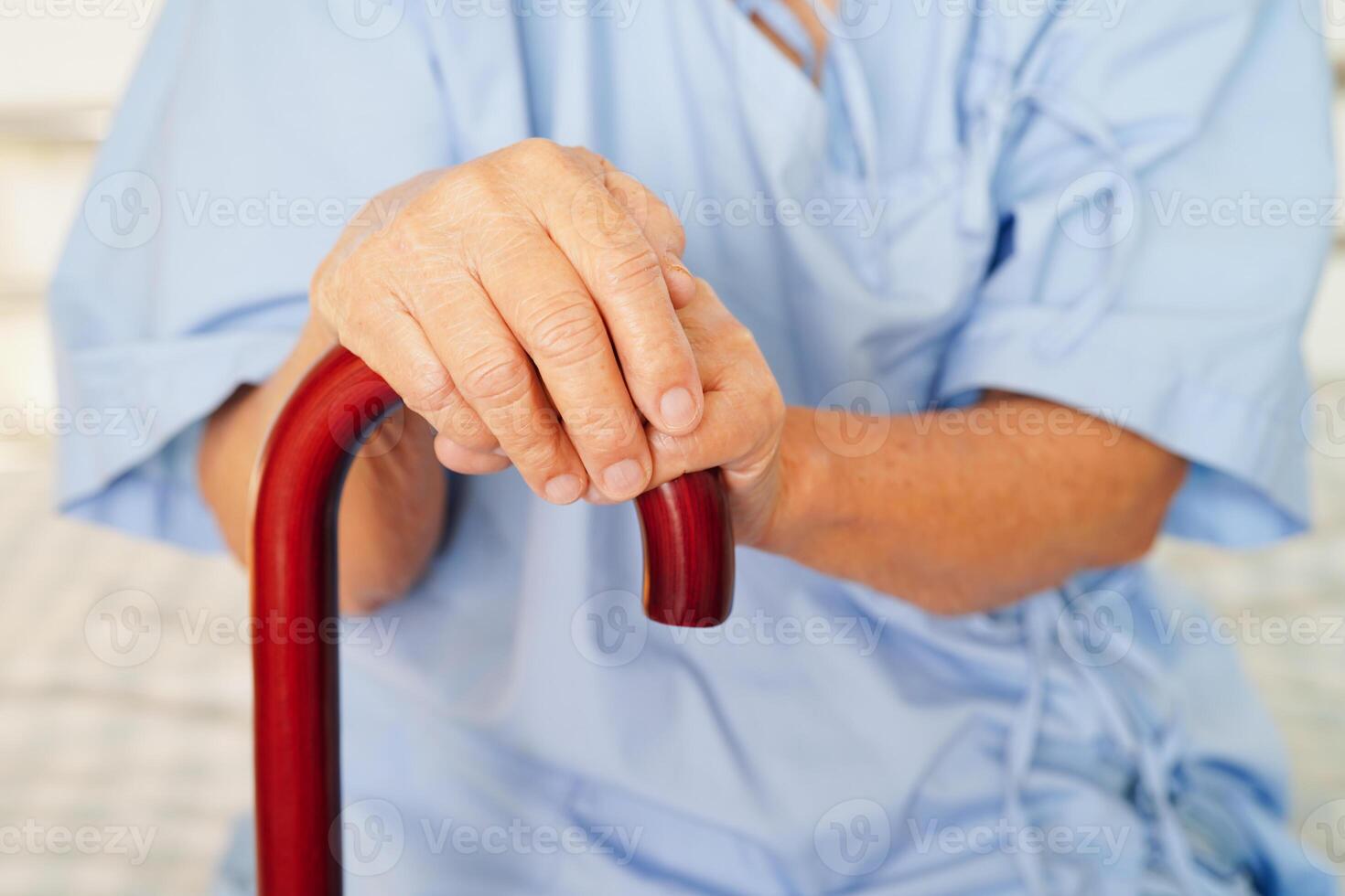Asian elderly disability woman patient holding walking stick in wrinkled hand at hospital. photo