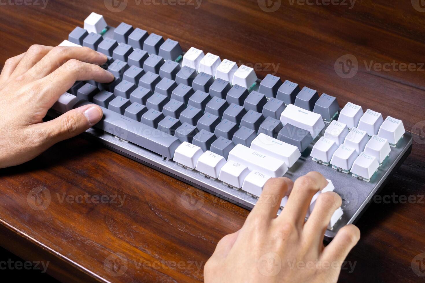 A modern mechanical keyboard and hands on a wooden table. After some edits. photo