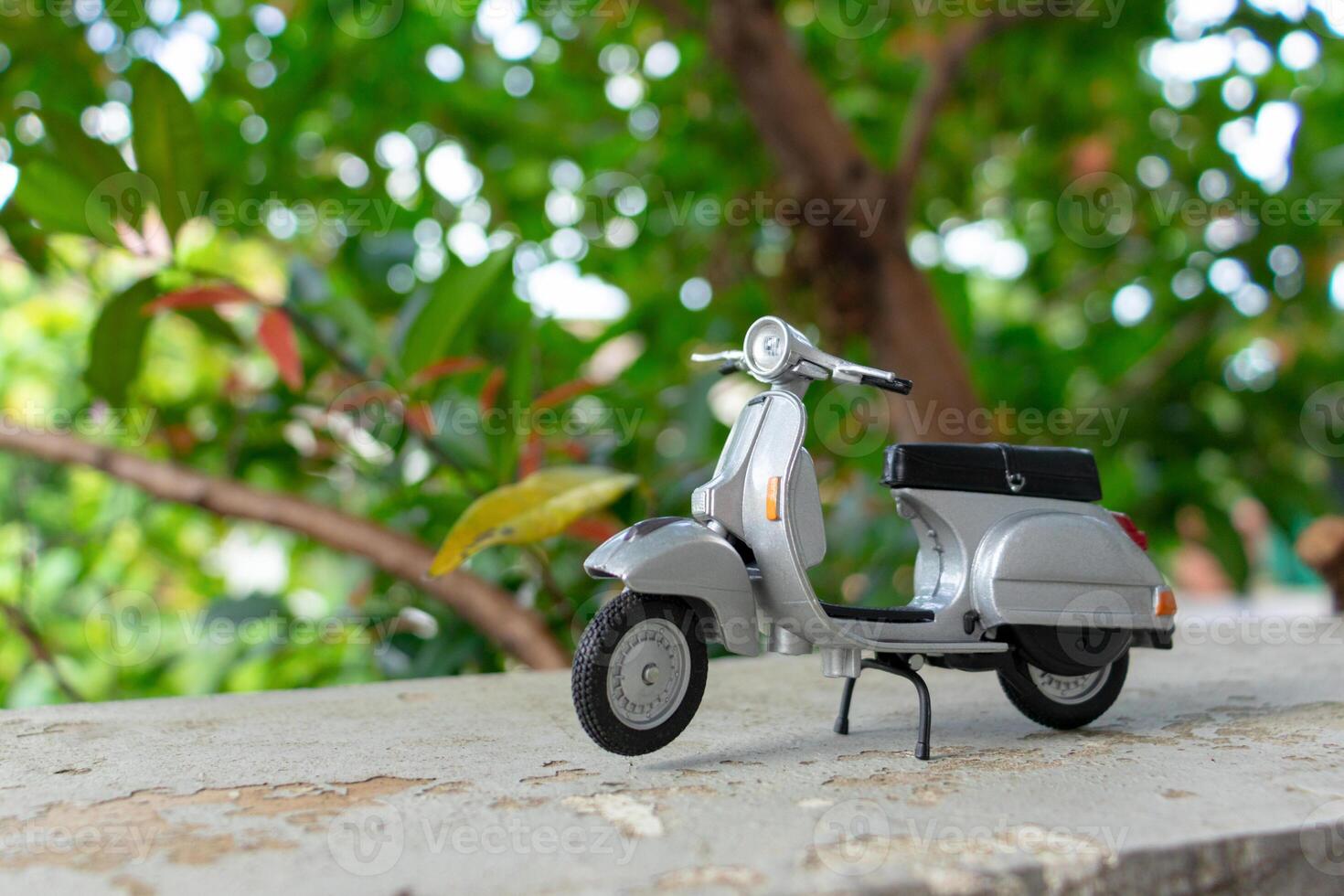Miniature classic scooter on the cement floor with nature background. After some edits. photo