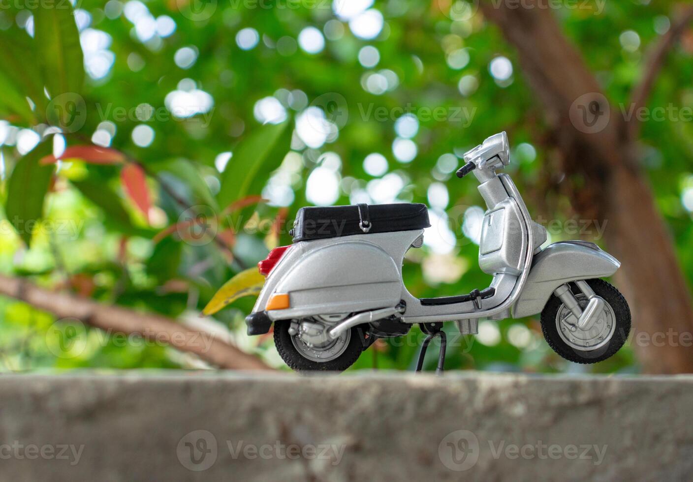 Miniature classic scooter on the cement floor with nature background. After some edits. photo