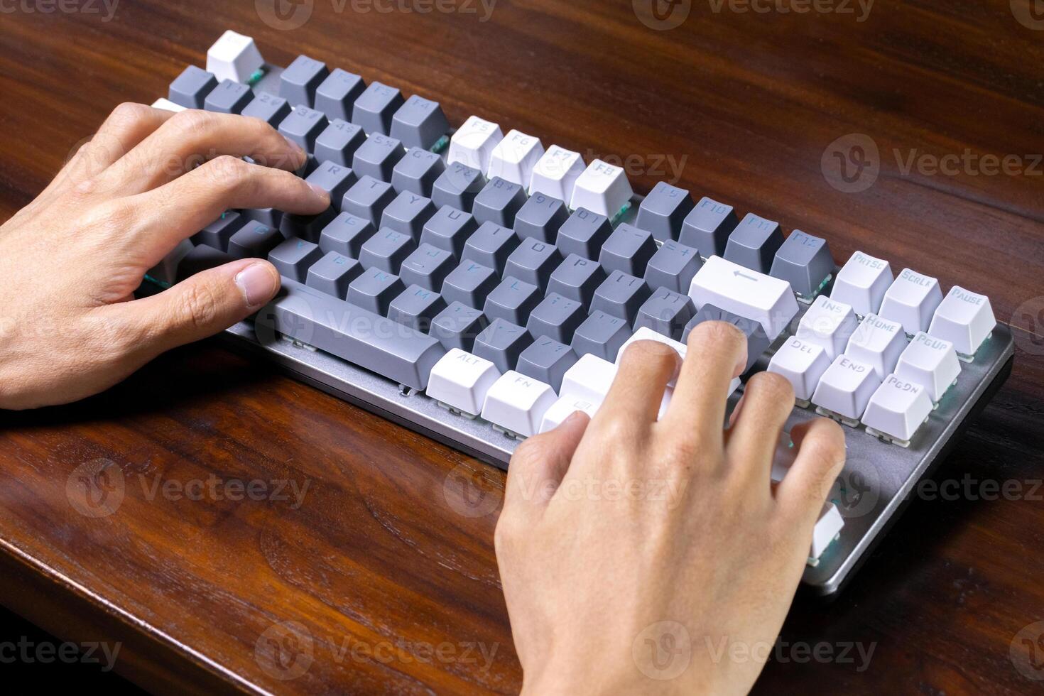 A modern mechanical keyboard and hands on a wooden table. After some edits. photo