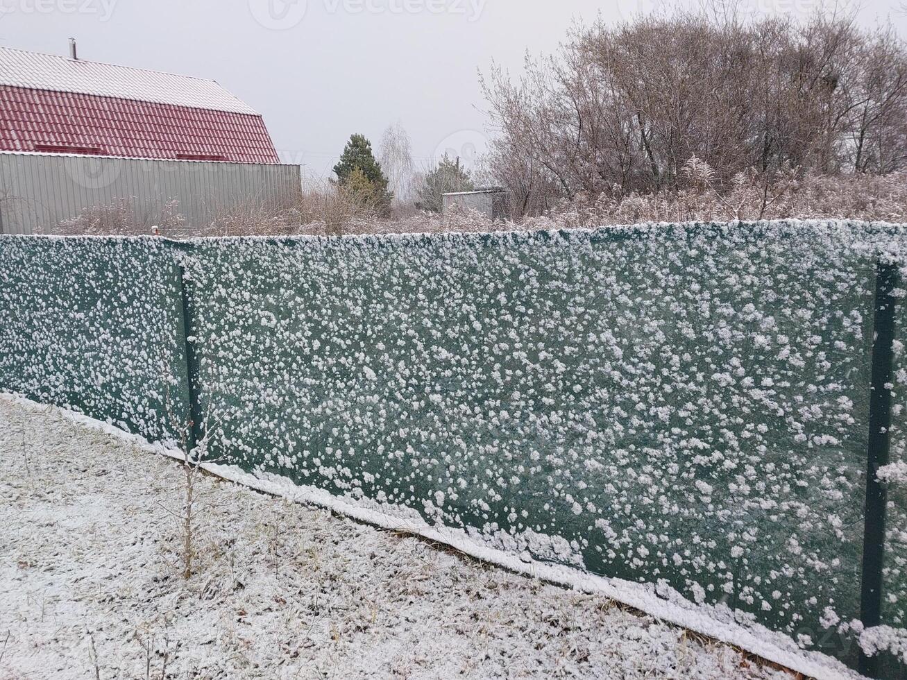 Snow fell on the fence in the village photo