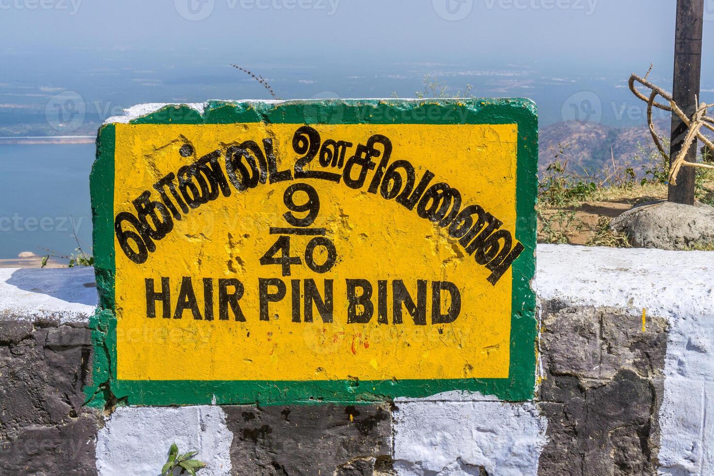 A sign indicating the 9th hair pin bend on the road from Pollachi to Valparai with the Aliyar reservoir on the background. photo