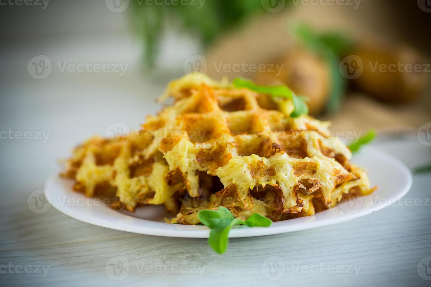 fried potato waffles with cheese in a plate on wooden table. photo