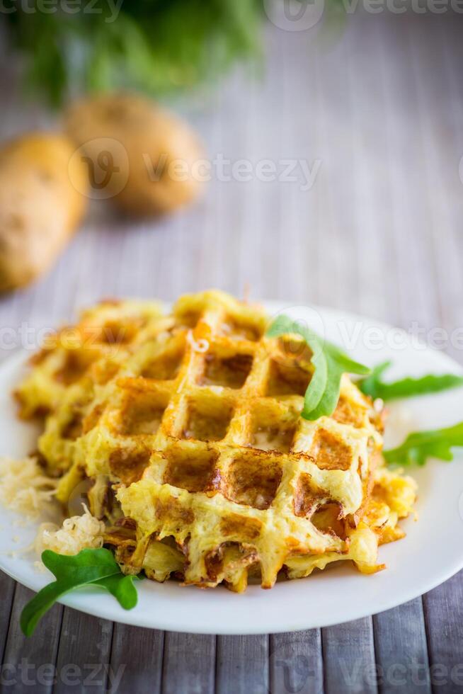 fried potato waffles with cheese in a plate on wooden table. photo