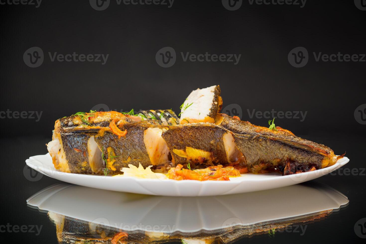 fish baked with spices and vegetables in the oven. photo