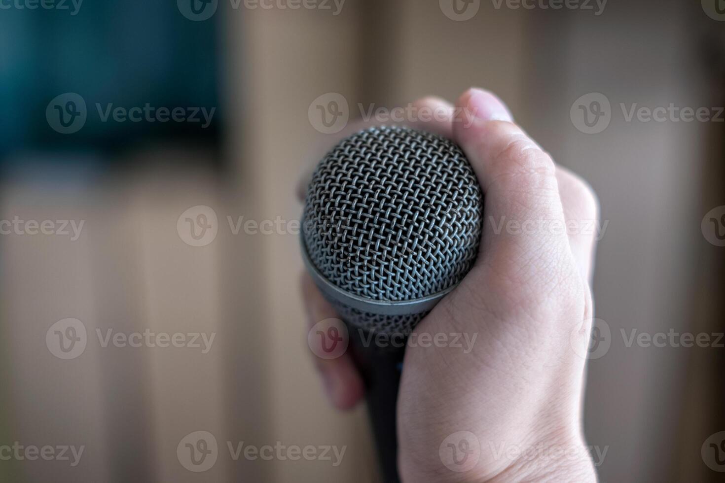 Hand holding a microphone on blur background photo