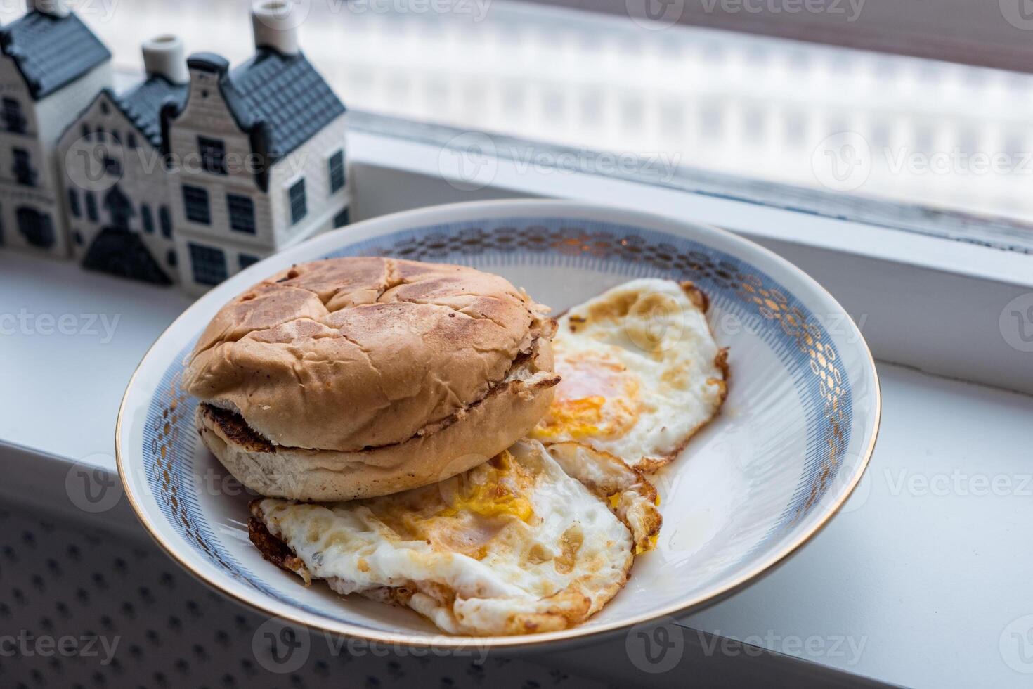 Hamburger bun scorched with fried eggs in plate photo